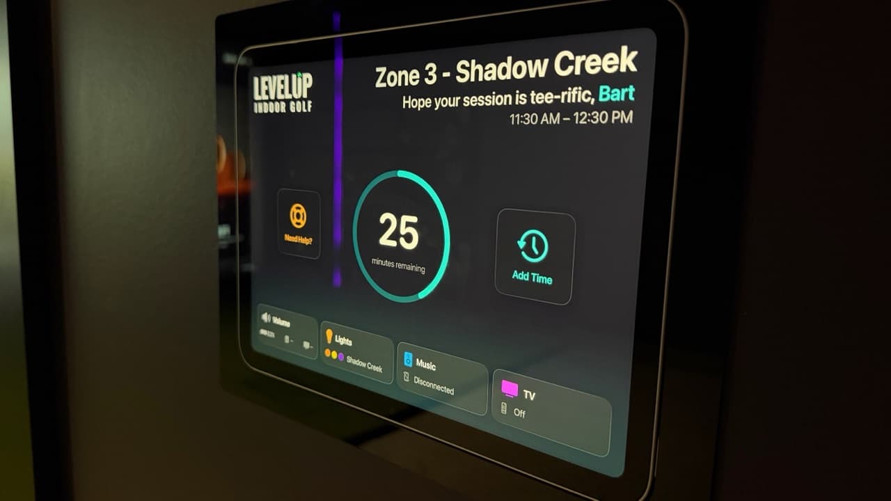 Wall-mounted iPad zone controller in a private bay at LevelUp Indoor Golf in Stoney Creek, showing session time remaining and lighting, audio, and TV controls